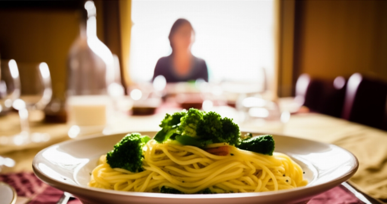 Gemütliche Szene mit einem Teller Pasta mit Brokkoli auf einem gedeckten Tisch, mit einer unscharfen kaukasischen Person im Hintergrund, die das Essen genießt.
