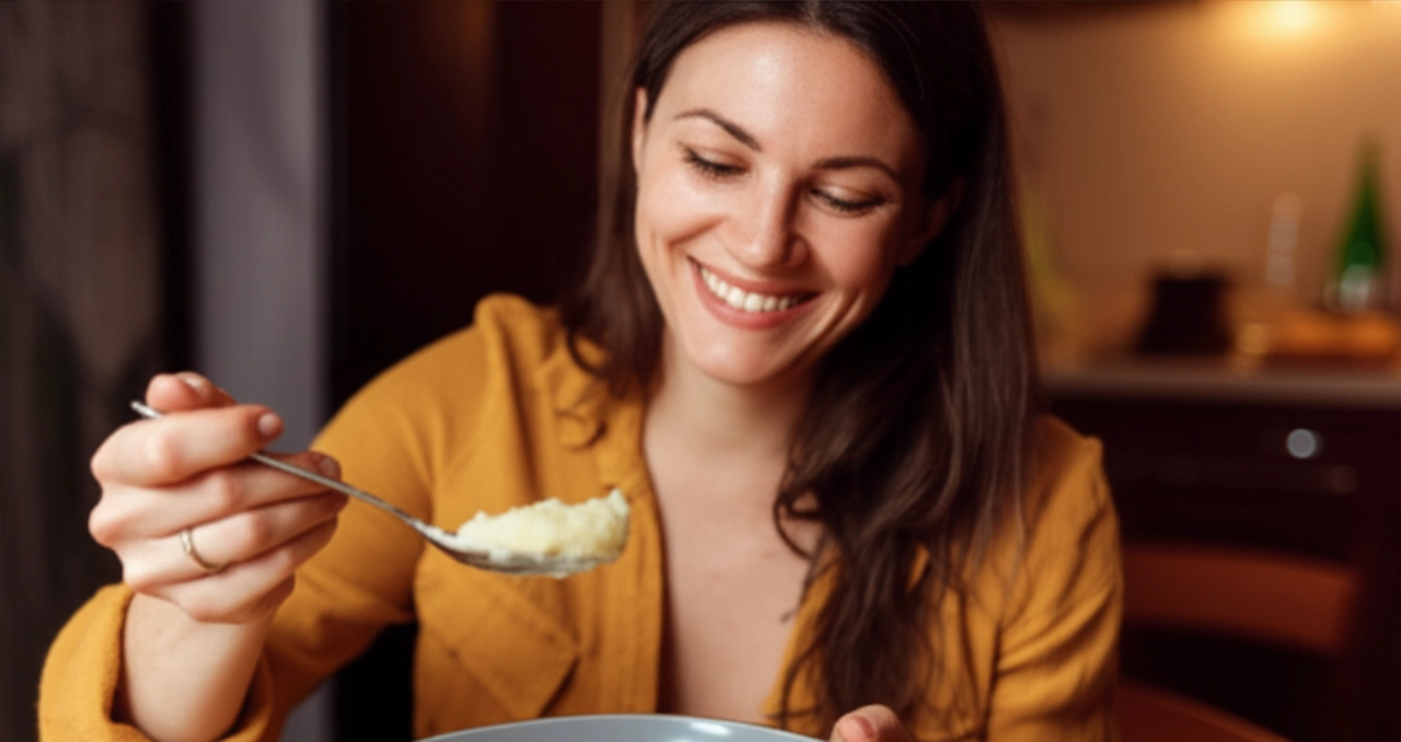 A smiling and satisfied Caucasian woman is about to enjoy a spoonful of creamy mashed potatoes, in a home setting.